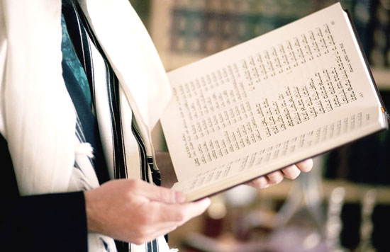 Person reading from a Jewish prayer book during daily prayer